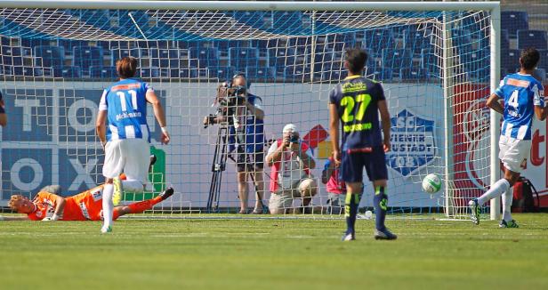 Ein Fußballspiel mit Spielern in blauen und orangefarbenen Trikots vor einem Tor.