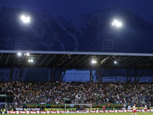 Ein Fußballstadion mit Zuschauern vor einer Bergkulisse bei Nacht.