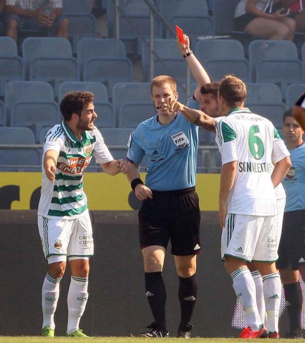 Ein Fußballschiedsrichter zeigt einem aufgeregten Spieler die Rote Karte.