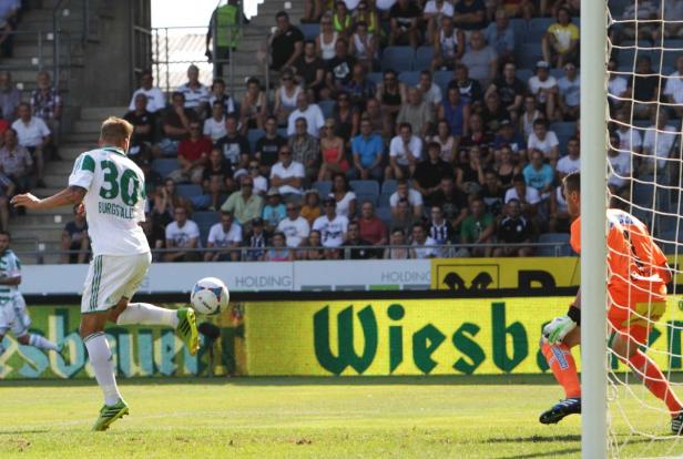 Ein Fußballspieler schießt den Ball in Richtung des Tors, während der Torwart bereitsteht.