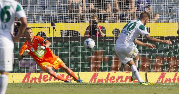 Ein Fußballspieler schießt einen Ball auf das Tor, während der Torwart versucht, ihn abzuwehren.