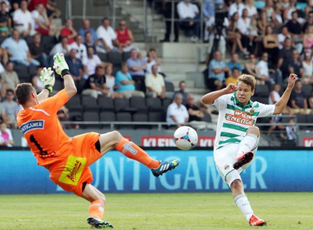 Ein Fußballspieler schießt den Ball, während der Torwart versucht, ihn abzuwehren.