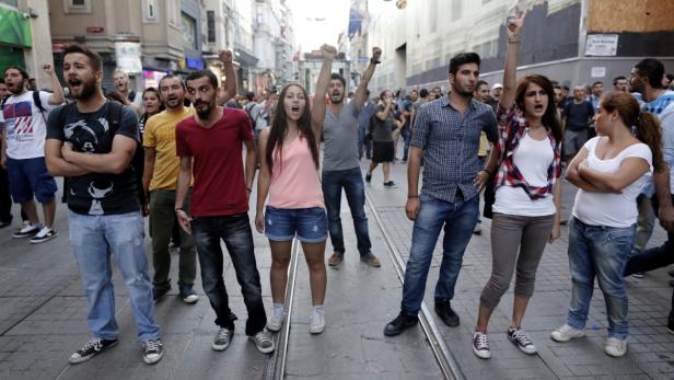 Eine Gruppe von Menschen demonstriert auf einer Straße und ruft Parolen.