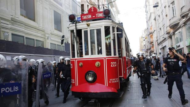 Polizisten stehen vor einer roten Straßenbahn in Istanbul.