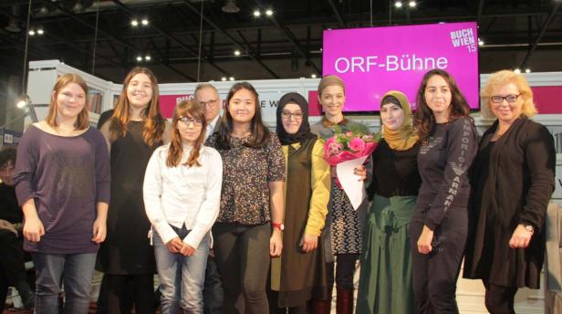 Eine Gruppe von Frauen und ein Mann posieren vor einer Bühne der „Buch Wien 15“.