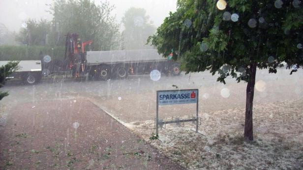 Ein schweres Hagelwetter mit einem LKW und einem Sparkassen-Schild im Vordergrund.