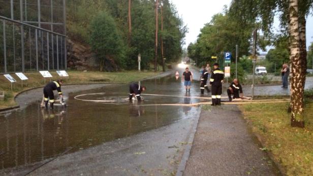 Feuerwehrleute pumpen Wasser von einer überfluteten Straße ab.