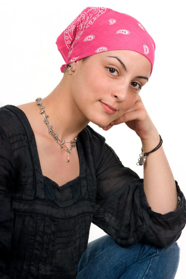 Eine Frau mit einem rosa Kopftuch und einer silbernen Halskette posiert.