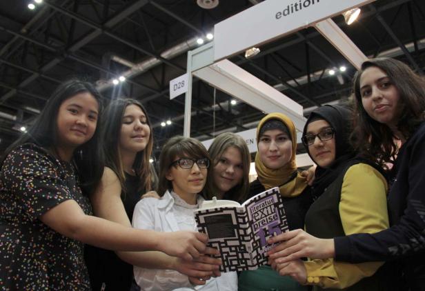 Eine Gruppe junger Frauen hält ein Buch mit dem Titel „Literaturpreise“ in den Händen.