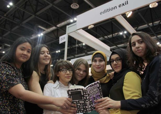 Eine Gruppe junger Frauen präsentiert ein Buch mit dem Titel „Literaturpreise“ am Stand „edition exil“.