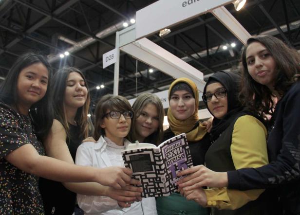 Eine Gruppe junger Frauen hält ein Buch mit dem Titel „Literaturpreise“ in die Kamera.