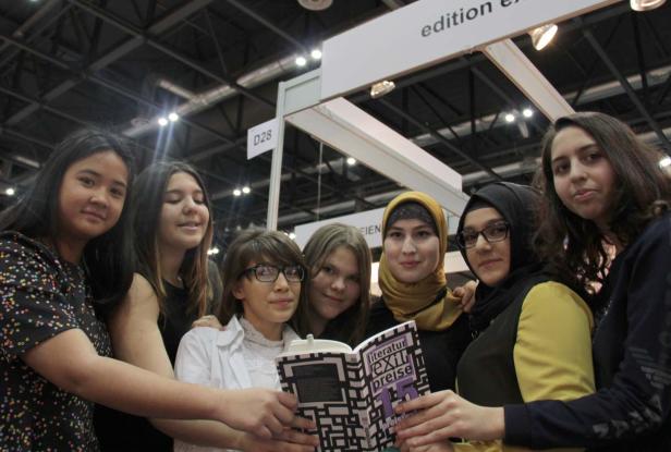 Eine Gruppe junger Frauen hält gemeinsam ein Buch mit dem Titel „Literaturpreise“.