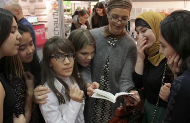 Eine Gruppe junger Frauen unterschiedlicher Herkunft betrachtet gemeinsam ein Buch.