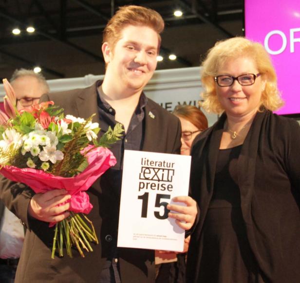 Ein Mann hält einen Blumenstrauß und eine Urkunde des Literaturpreises „exit 15“.