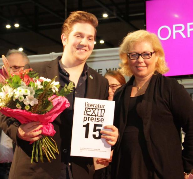 Ein Mann mit Blumenstrauß und eine Frau halten eine Urkunde für den Literaturpreis „Text & Sprache“.