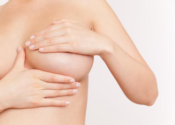 Eine Frau untersucht ihre Brust mit ihren Händen.