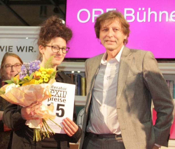 Eine Frau mit Blumenstrauß und ein Mann stehen auf der „OP Bühne“.