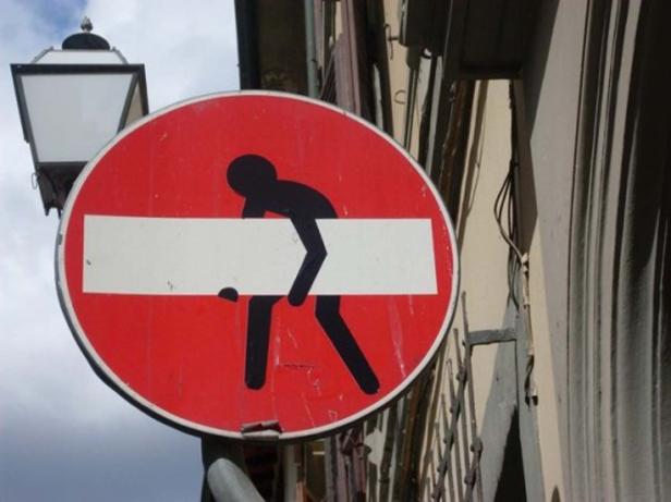 Ein ungewöhnliches Verkehrsschild zeigt eine stilisierte Figur, die einen Balken trägt.