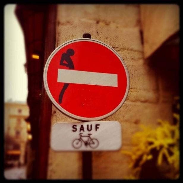 Ein Verkehrsschild mit einem stiliserten, laufenden Mann und dem Hinweis „SAUF“ mit Fahrradsymbol.