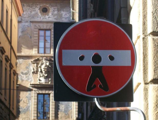 Ein ungewöhnliches Verkehrsschild mit einer stilisierten Darstellung einer Person im Pranger.
