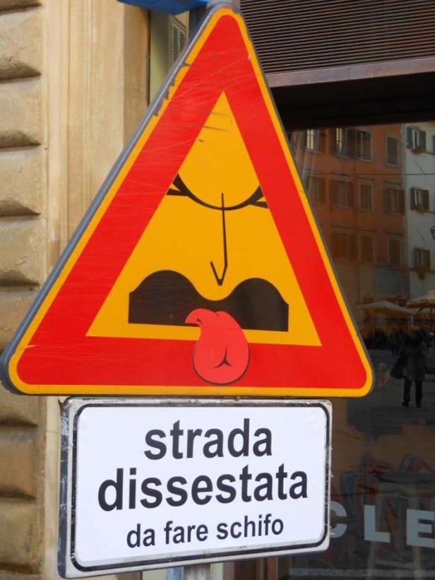 Ein Verkehrsschild mit einer Karikatur, die eine holprige Straße andeutet.