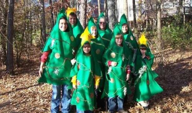 Eine Gruppe von Menschen, verkleidet als Weihnachtsbäume, steht im Wald.