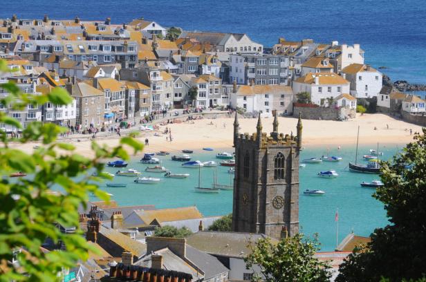 Blick auf St Ives in Cornwall mit Kirche, Strand und Booten.