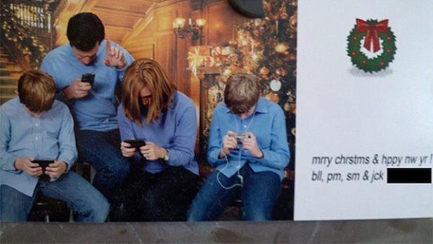 Eine Familie sitzt vor einem Weihnachtshintergrund und starrt auf ihre Smartphones.