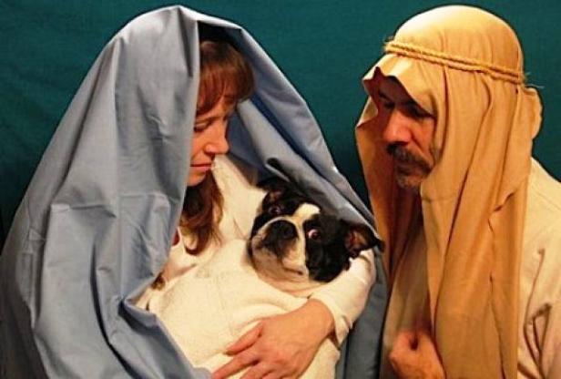 Eine Frau und ein Mann verkleidet als Maria und Josef mit einem Hund als Jesuskind.
