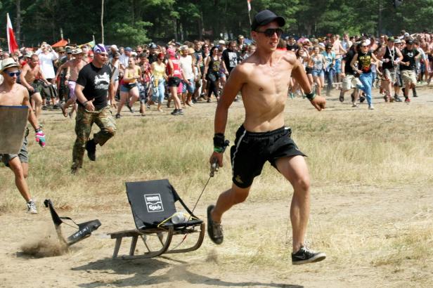 Ein Mann zieht einen Schlitten mit einem Stuhl über ein Feld, während andere Menschen rennen.