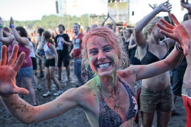 Eine junge Frau lächelt mit Farbe im Gesicht auf einem Festival.