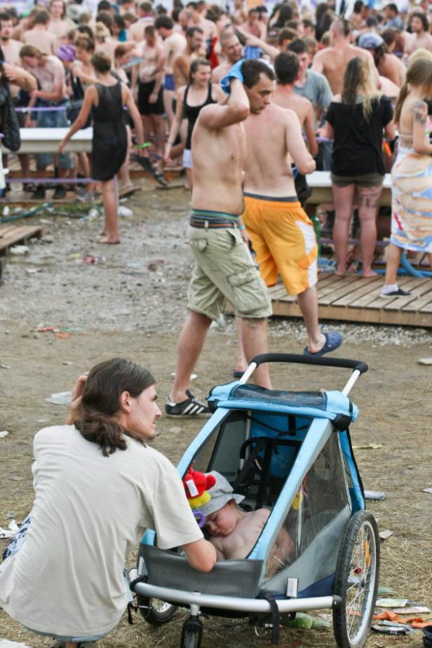 Ein schlafendes Kind liegt in einem Kinderwagen inmitten einer Menschenmenge.