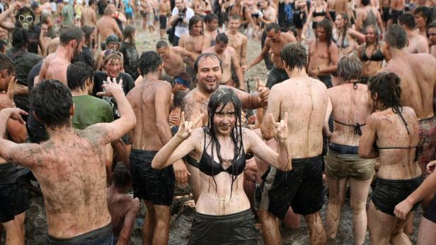 Eine Menschenmenge, die mit Schlamm bedeckt ist, feiert ausgelassen.