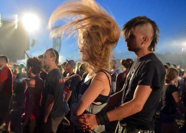 Ein Paar umarmt sich auf einem Konzert vor einer Menschenmenge.