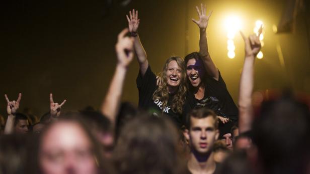 Zwei Frauen jubeln auf einem Konzert, während andere Konzertbesucher die Hände heben.