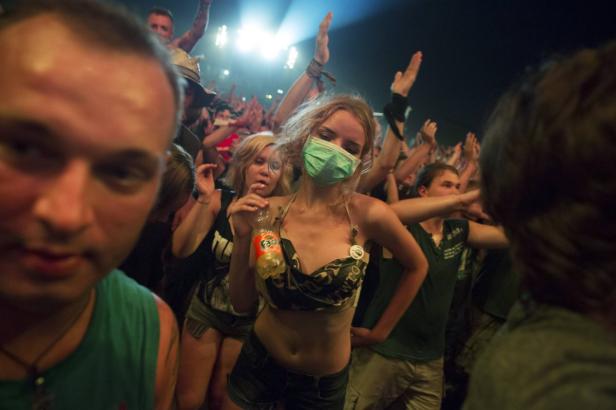 Eine junge Frau mit Mundschutz und einer Fanta-Flasche auf einem Konzert.