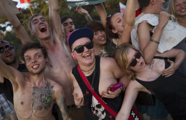 Eine Gruppe junger, ausgelassen feiernder Menschen mit Tätowierungen und Piercings.