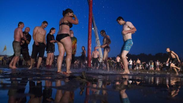 Eine Gruppe von Menschen steht unter einer Dusche im Freien.
