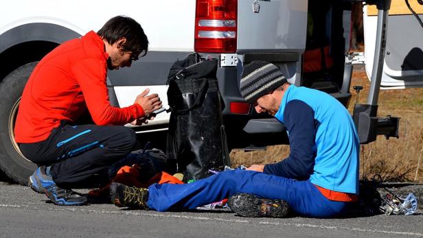 Zwei Männer sitzen vor einem Van und bereiten ihre Kletterausrüstung vor.