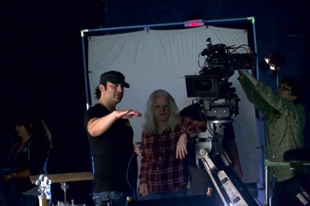 Drei Personen arbeiten an einem Filmset mit einer großen Kamera.