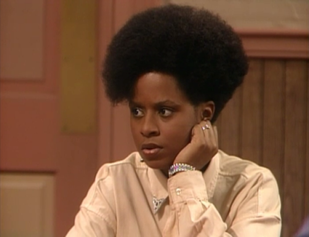 Eine junge Frau mit Afro-Frisur blickt nachdenklich zur Seite.