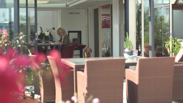 Eine Frau sitzt an einem Tisch und liest, während ein Hund zusieht.