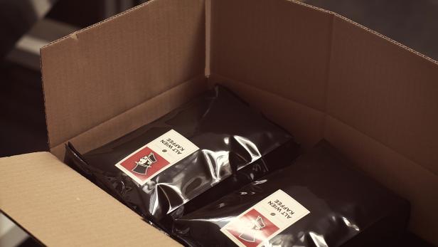 Zwei Packungen „Alt Wien Kaffee“ liegen in einem offenen Karton.
