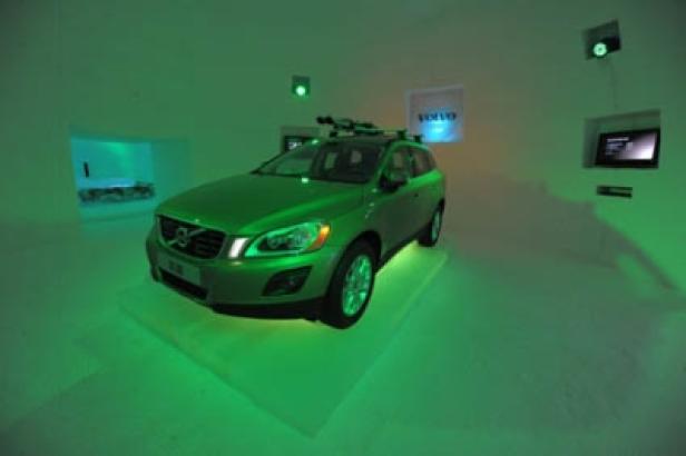 Ein grüner Volvo XC60 steht in einem Ausstellungsraum mit grüner Beleuchtung.