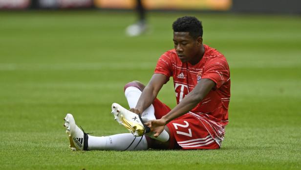 Ein Fußballspieler sitzt auf dem Rasen und zieht seinen Schuh an.