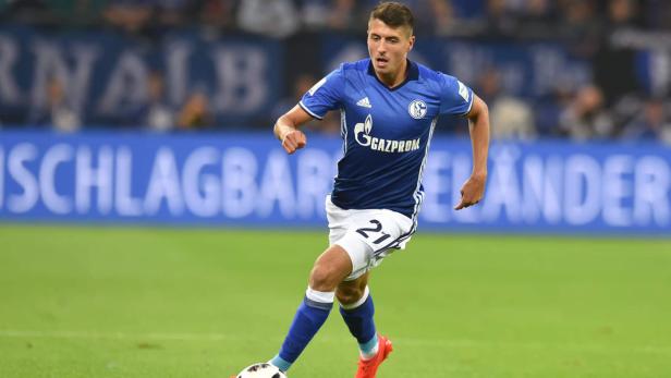 Ein Fußballspieler des FC Schalke 04 im blauen Trikot mit der Nummer 21 am Ball.