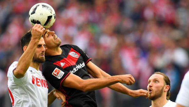 Ein Fußballspieler köpft den Ball, während zwei andere Spieler zusehen.