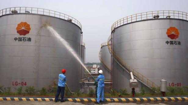 Zwei Arbeiter spritzen Wasser auf einen großen Tank von China National Petroleum Corporation.
