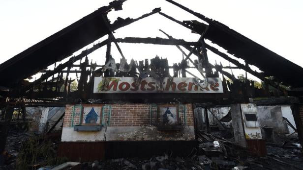 Die Ruine eines ausgebrannten Gebäudes mit einem Schild „Mostschenke“.
