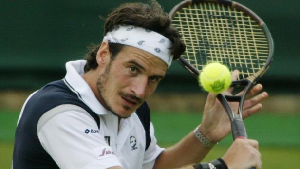 Ein Tennisspieler mit Stirnband schlägt einen gelben Tennisball mit seinem Schläger.